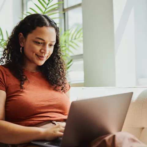 Young woman siting on couch on her laptop