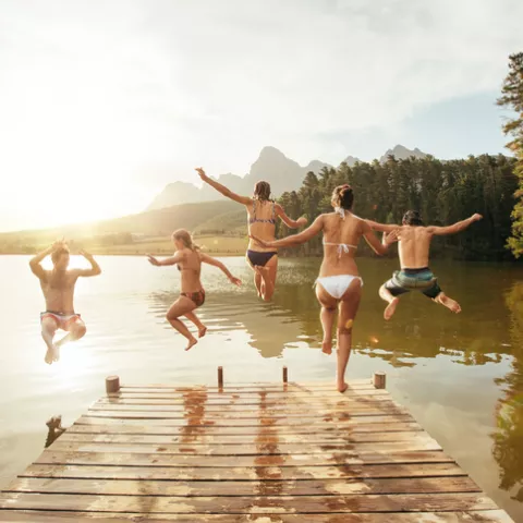 Kids jumping off a dock into a lake