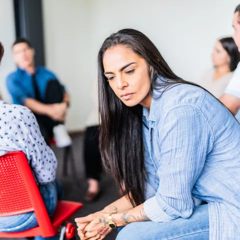 Sad adult woman during a group therapy at mental health center.