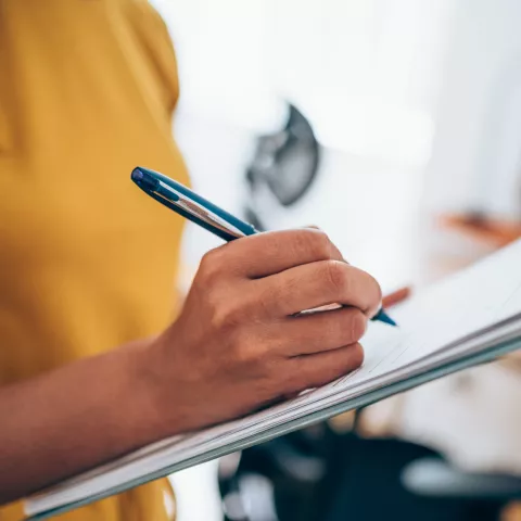 Woman hand writing on clipboard with a pen.