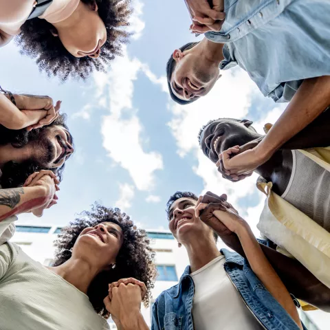 Group of people holding hands in a circle, bottom view