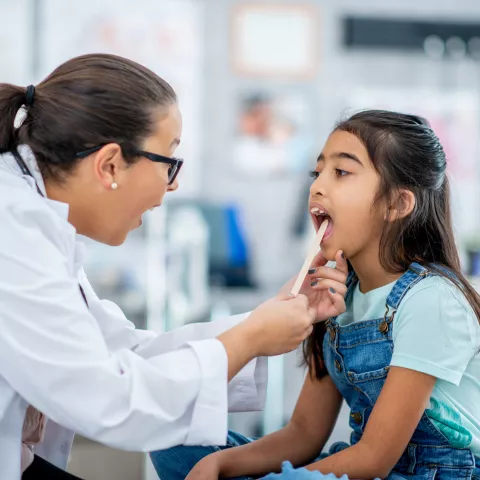 A little girl of Middle Eastern decent, sits up on an exam table during a routine check-up. 