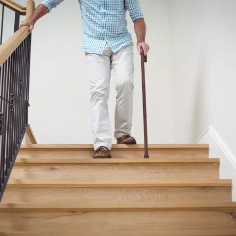 Senior man climbing downstairs with walking stick