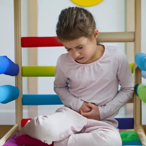 Child sitting in a play structure at daycare with stomach pain