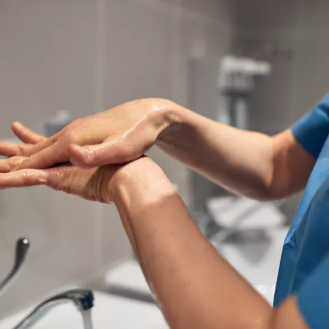 Close-up of a PSW washing his hands using a disinfectant dispenser - stock photo