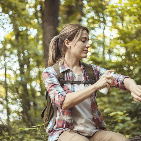Woman Applying Insect Repellent Against Mosquito and Tick During Hike in Nature
