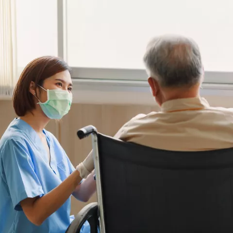 Young Asian woman nurse explaining information to elderly man patient in wheelchair 