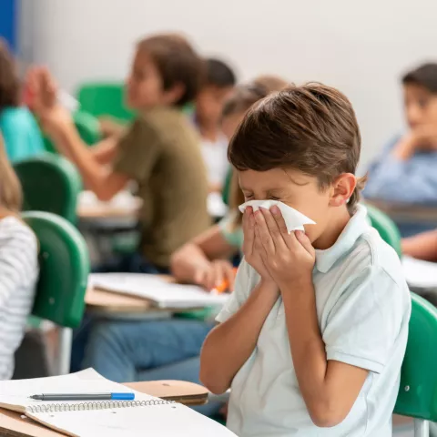 Sick boy at the school blowing his nose in class
