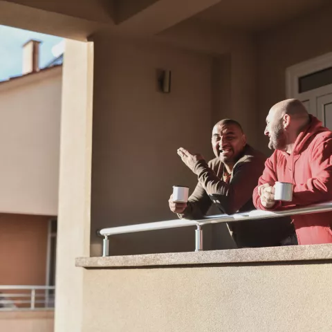 Two males enjoying coffee on their balcony