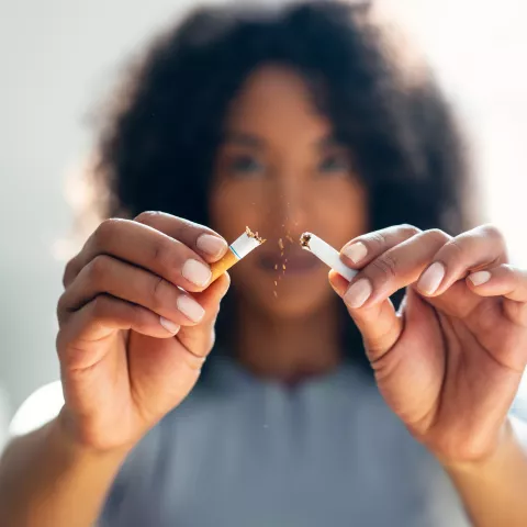 Woman breaking down cigarette to pieces. Quit smoking concept