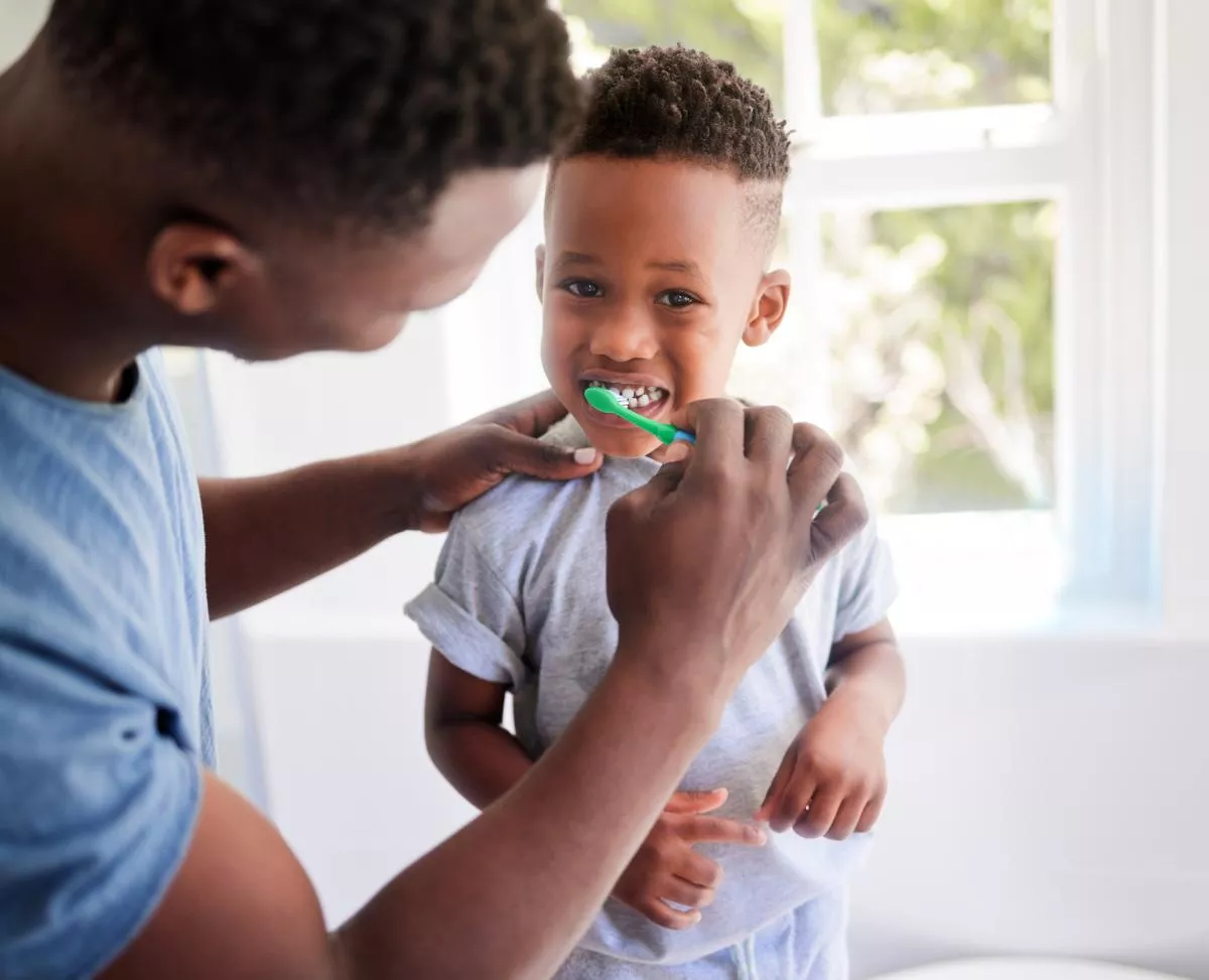 father brushing childs teeth