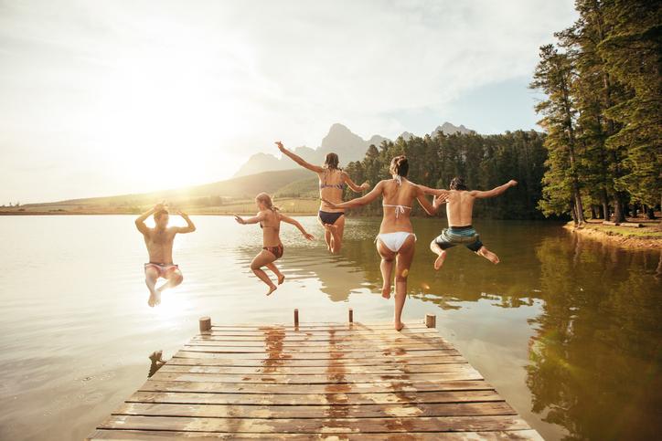 Kids jumping off a dock into a lake