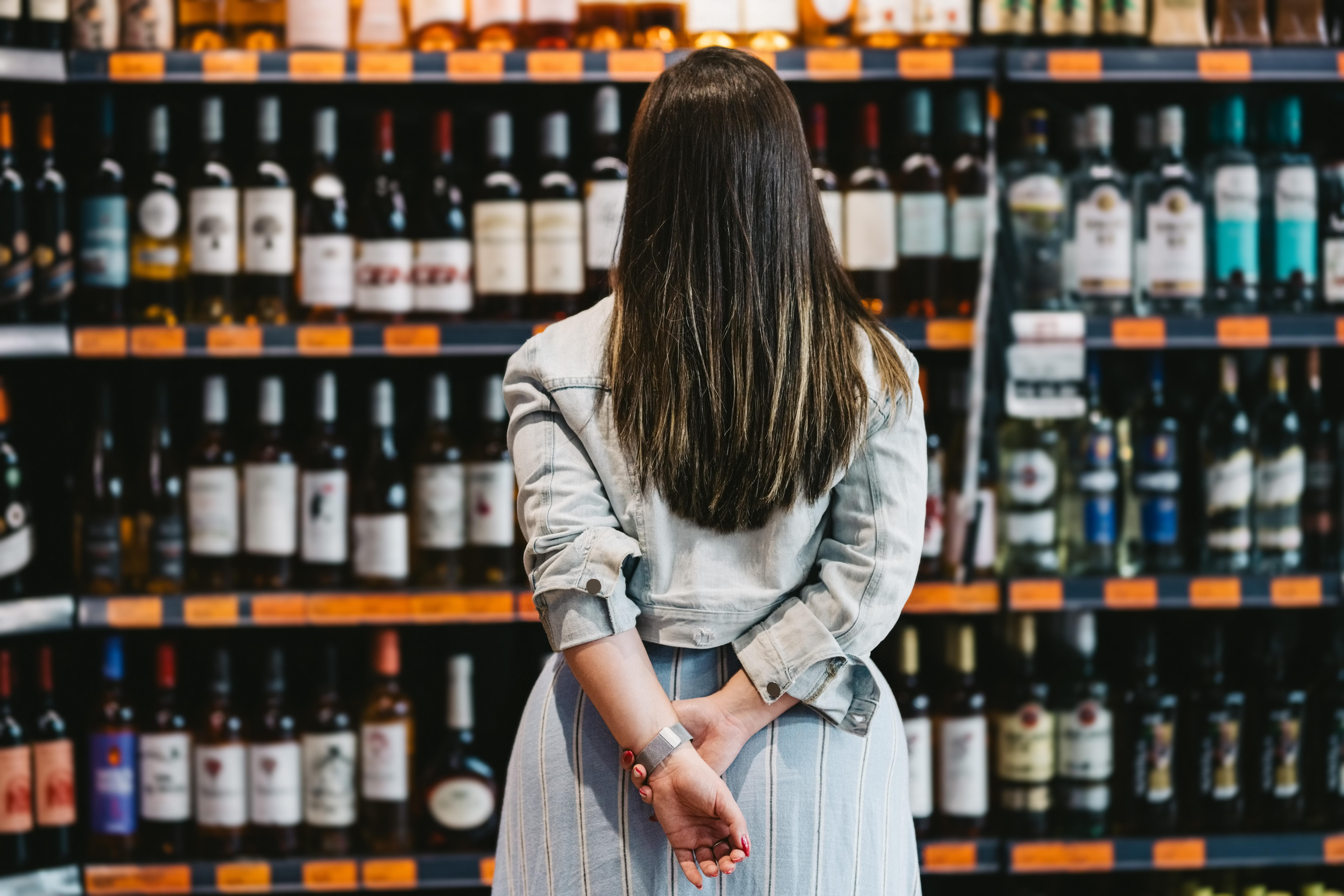 Woman customer looking at a rack of wine in supermarket