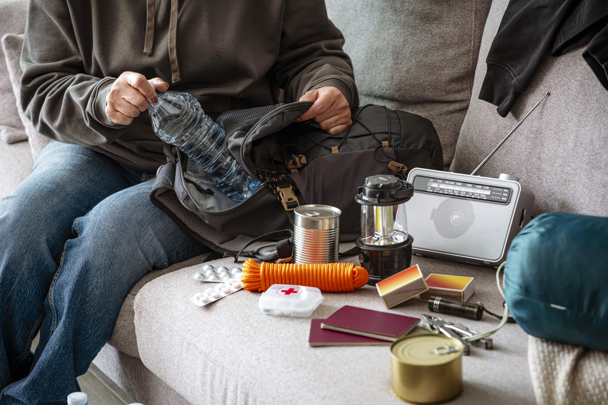 Woman filling emergency backpack with disaster emergency supplies