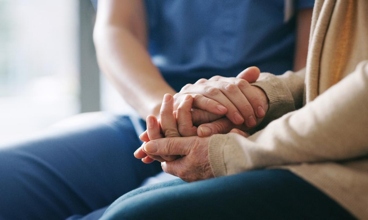 support worker holding patient hand
