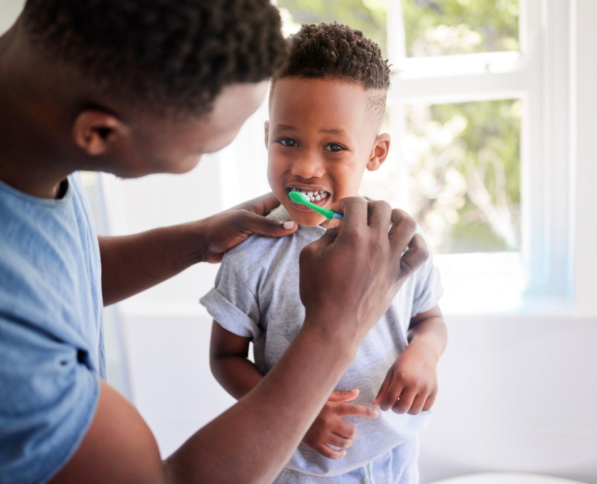 father brushing childs teeth