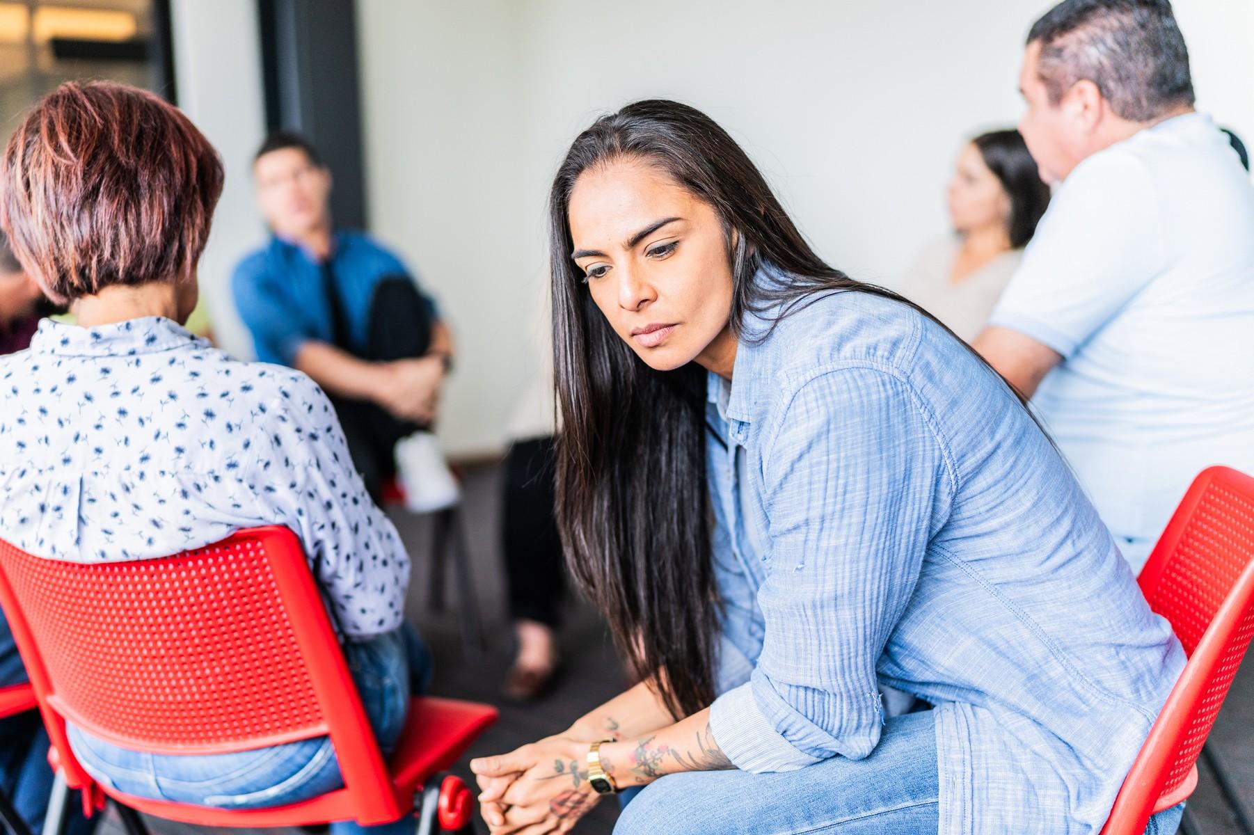 Sad adult woman during a group therapy at mental health center.