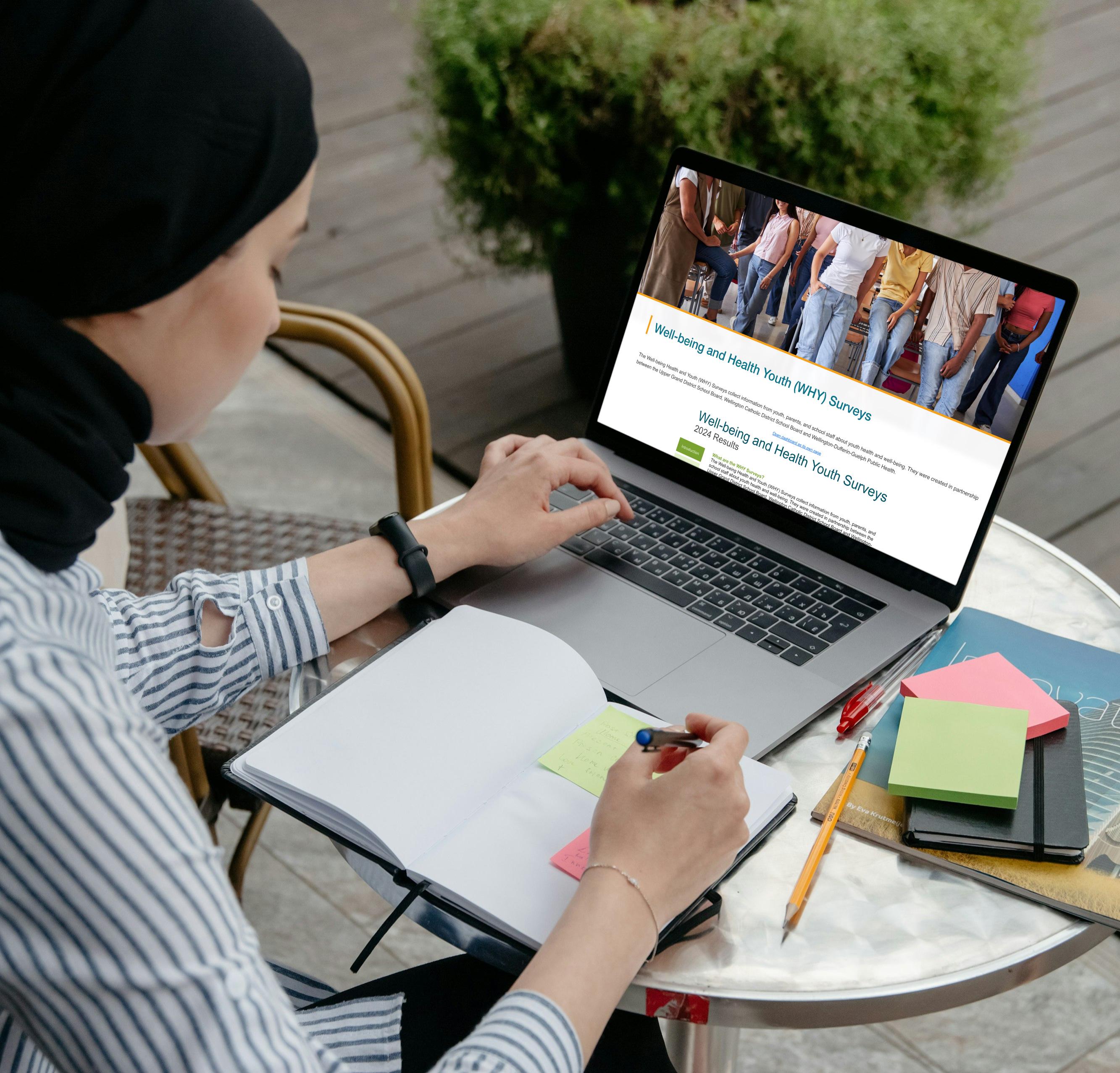 Woman looking at the WHY dashboard on her laptop at a cafe outdoors