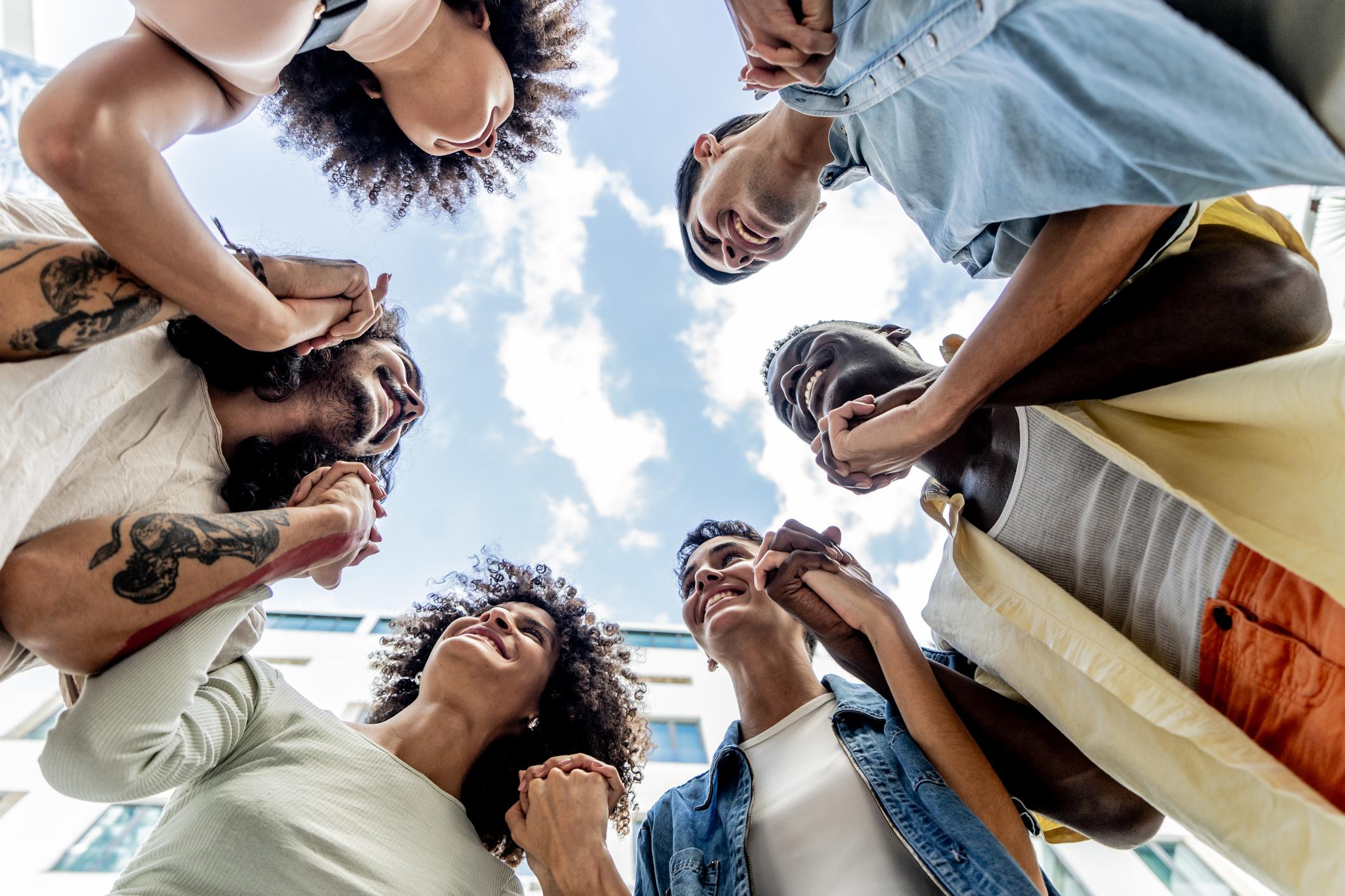 Group of people holding hands in a circle, bottom view