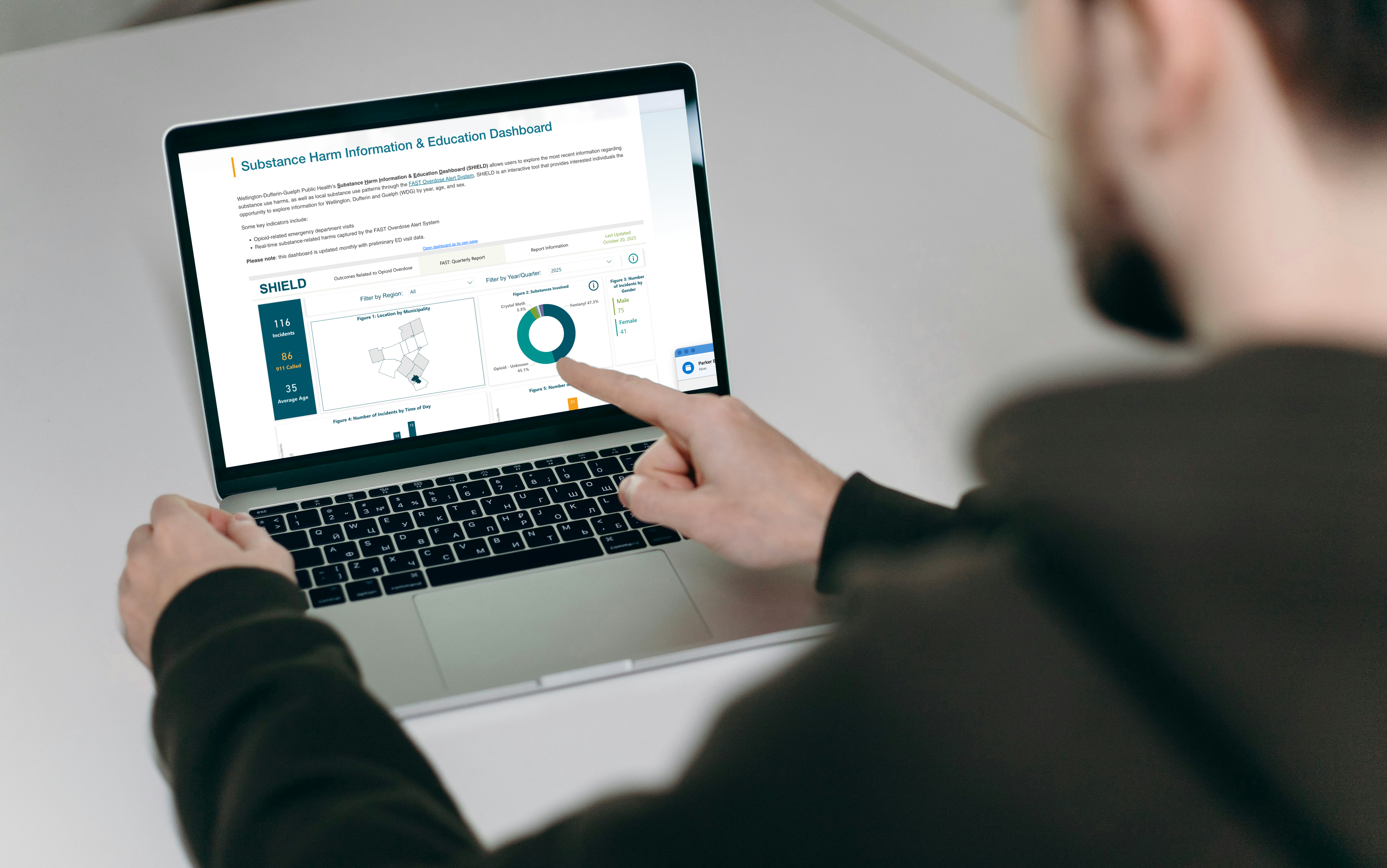 Man looking at the SHIELD dashboard sitting at his desk pointing at the screen