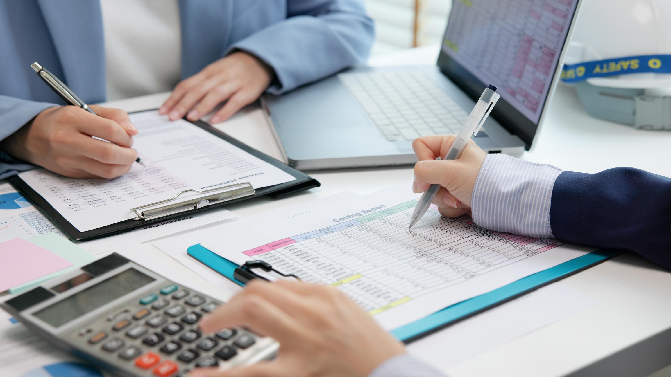 People at a table reviewing paper and electronic financial statements.