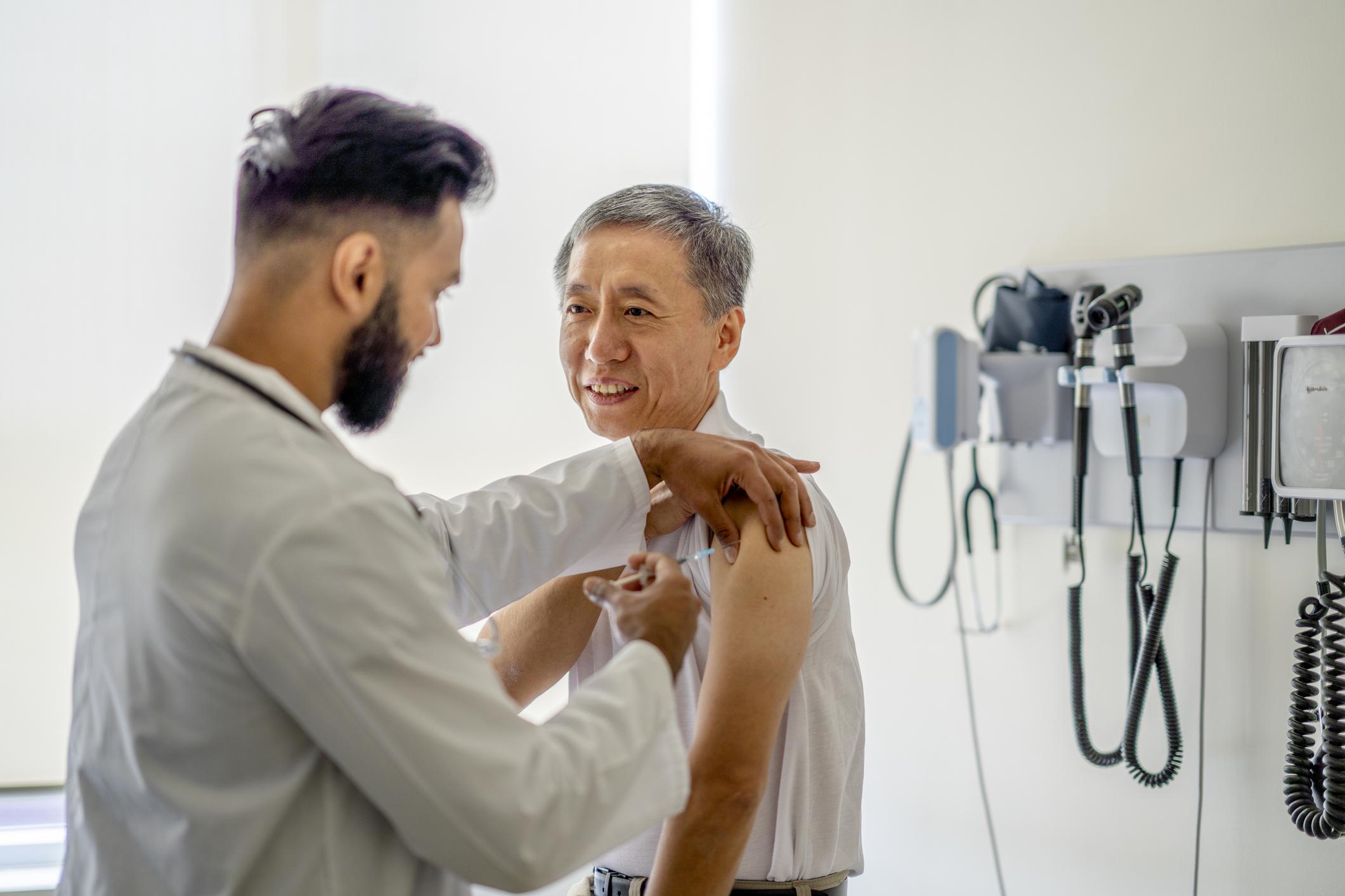 A male doctor administering a medical injection into a senior patient's arm.