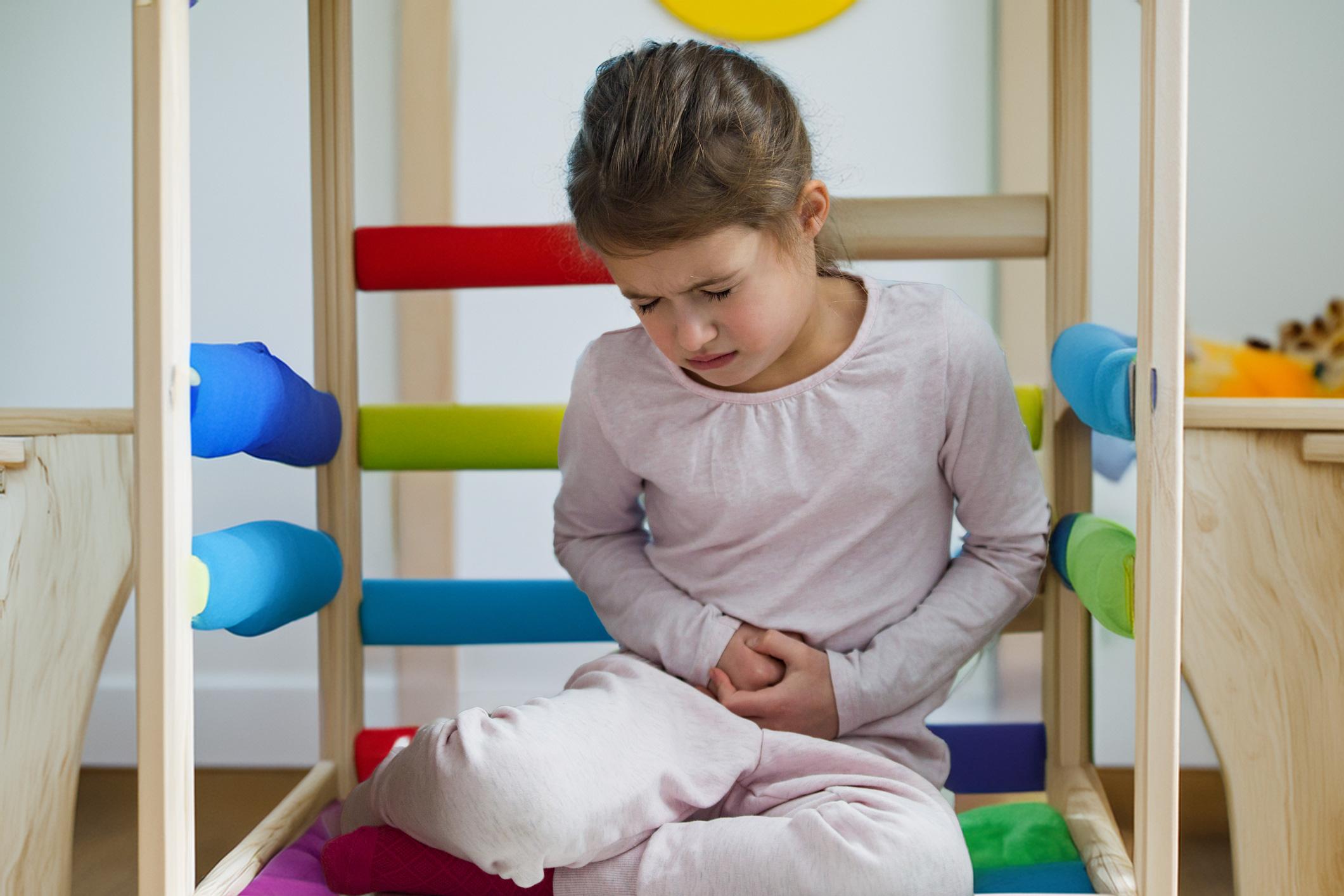 Child sitting in a play structure at daycare with stomach pain