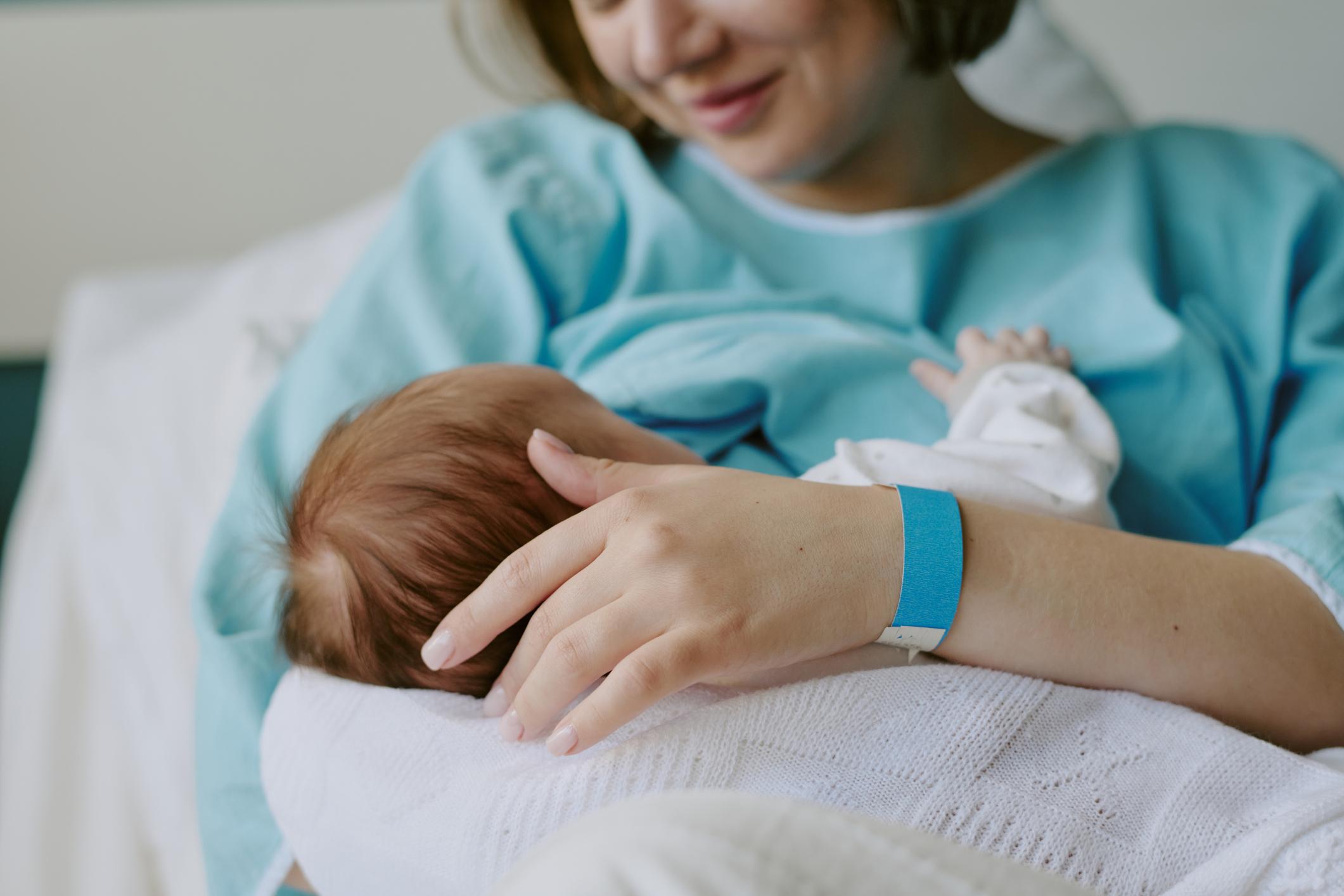 Mother Breastfeeding Newborn Baby in Hospital Room