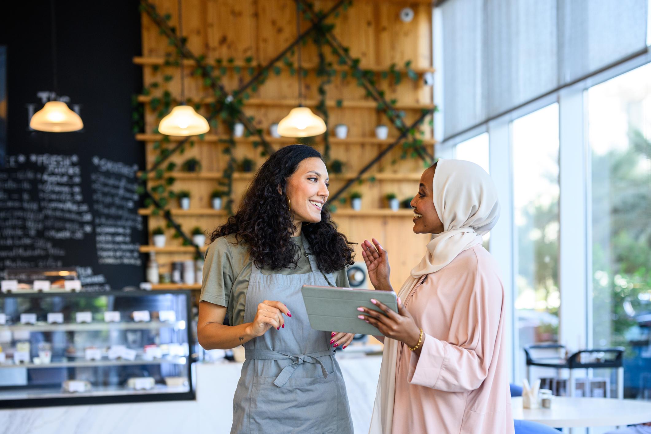 Two diverse women discussing small business strategy in a cafe 