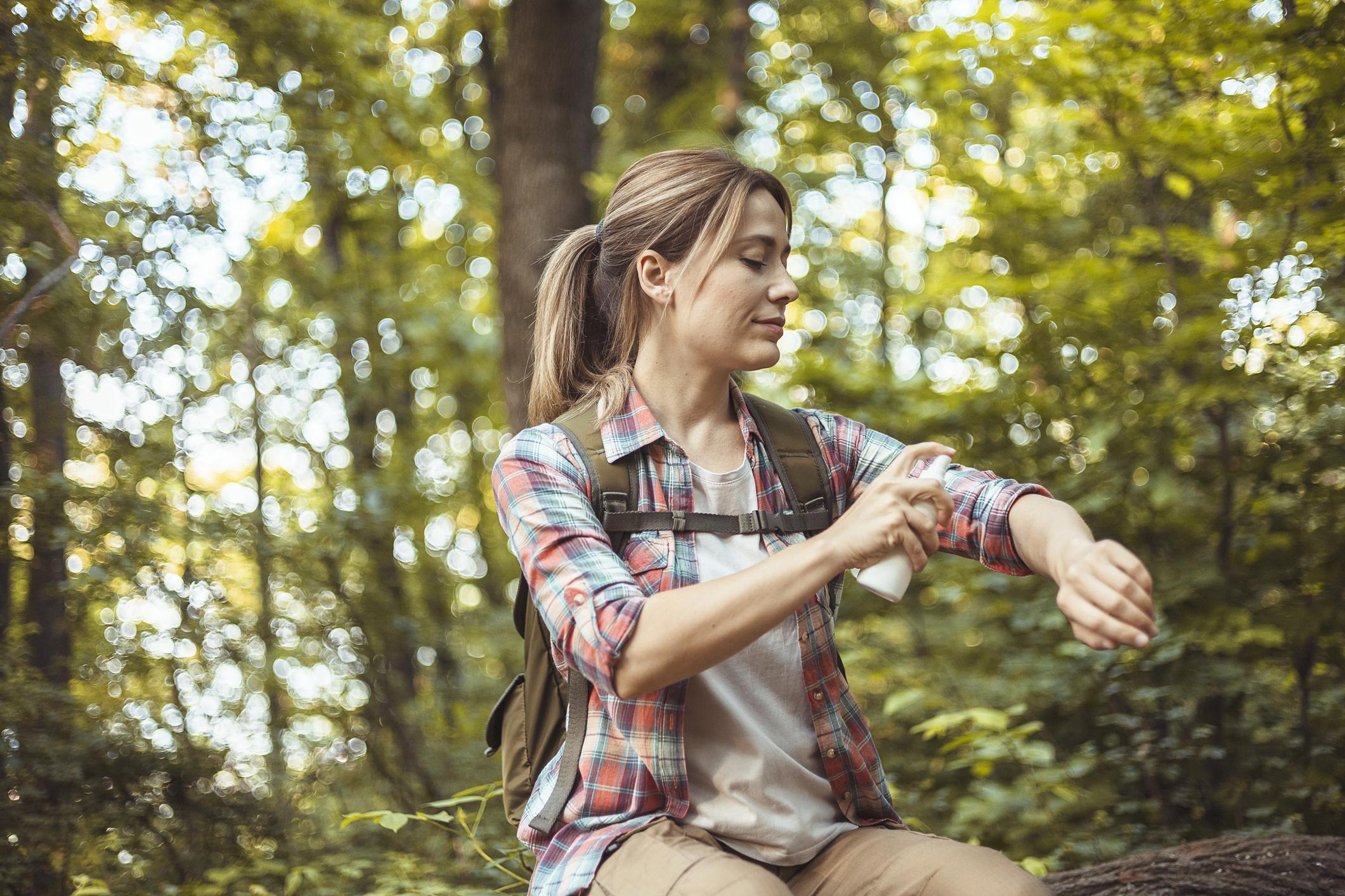 Woman Applying Insect Repellent Against Mosquito and Tick During Hike in Nature