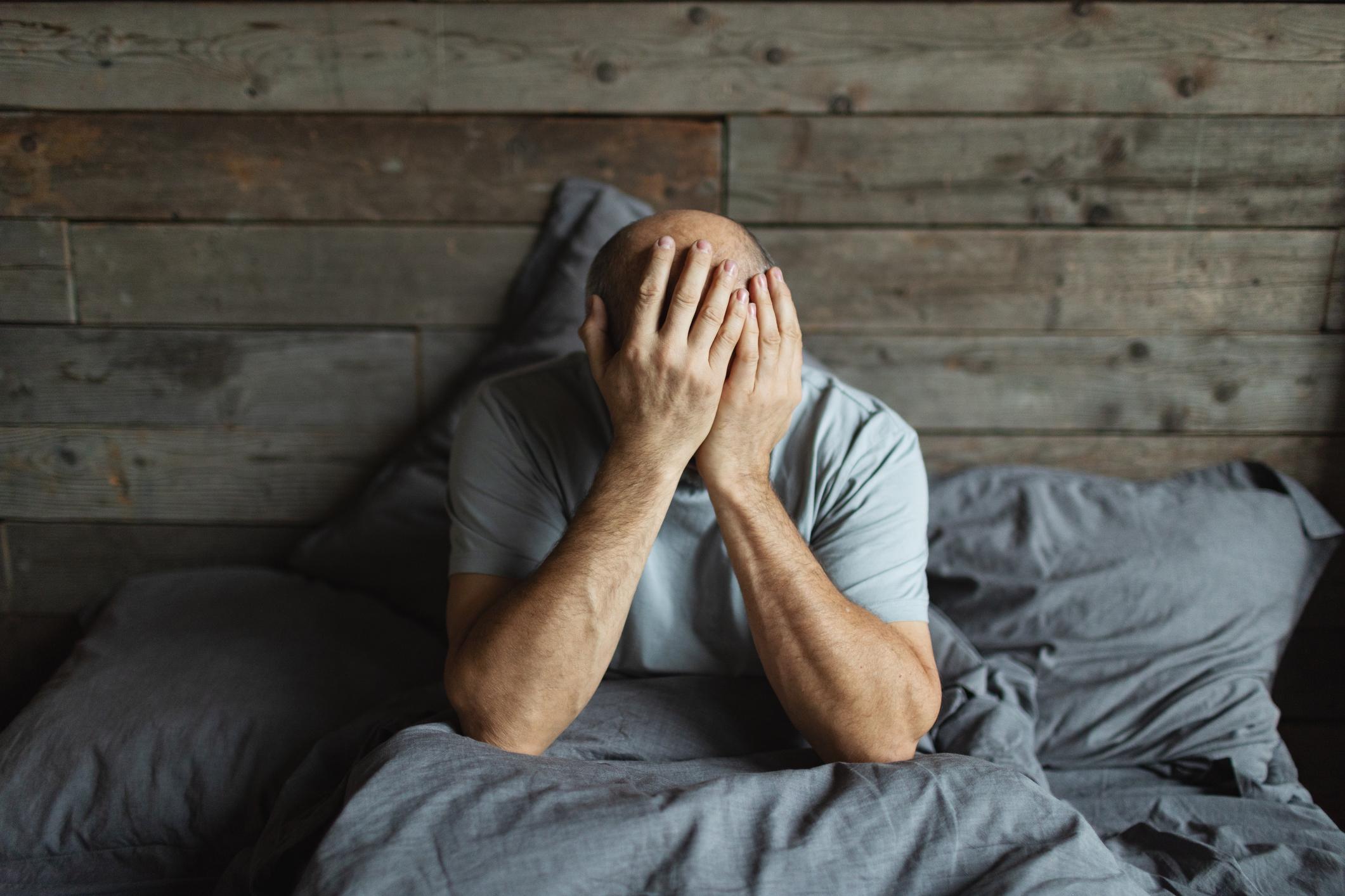 Mature man in bed with headache