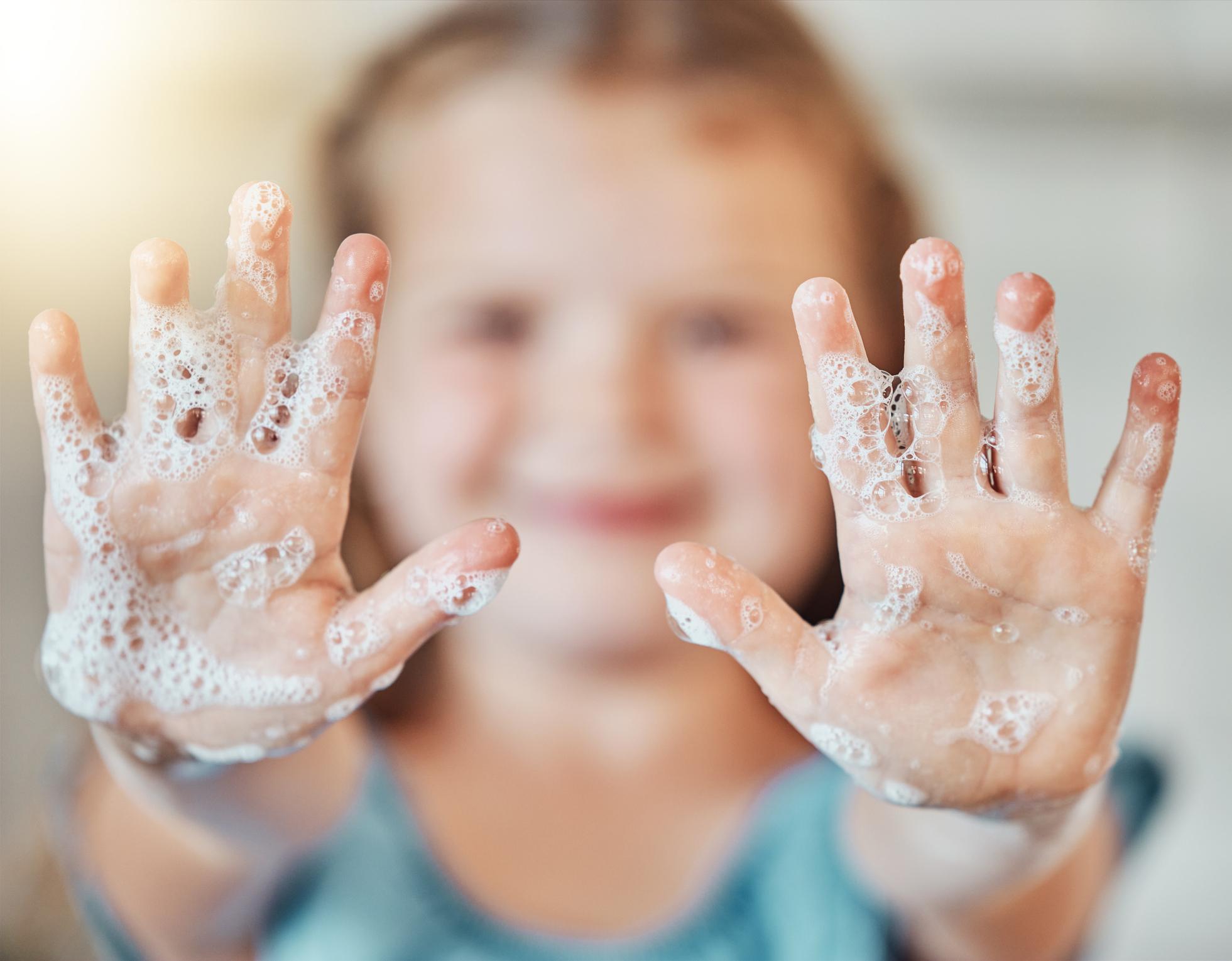 Girl holding her soapy hands up to the camera
