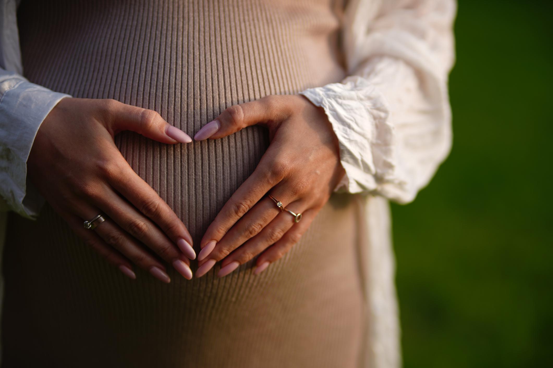 Pregnant woman making heart shape on her belly