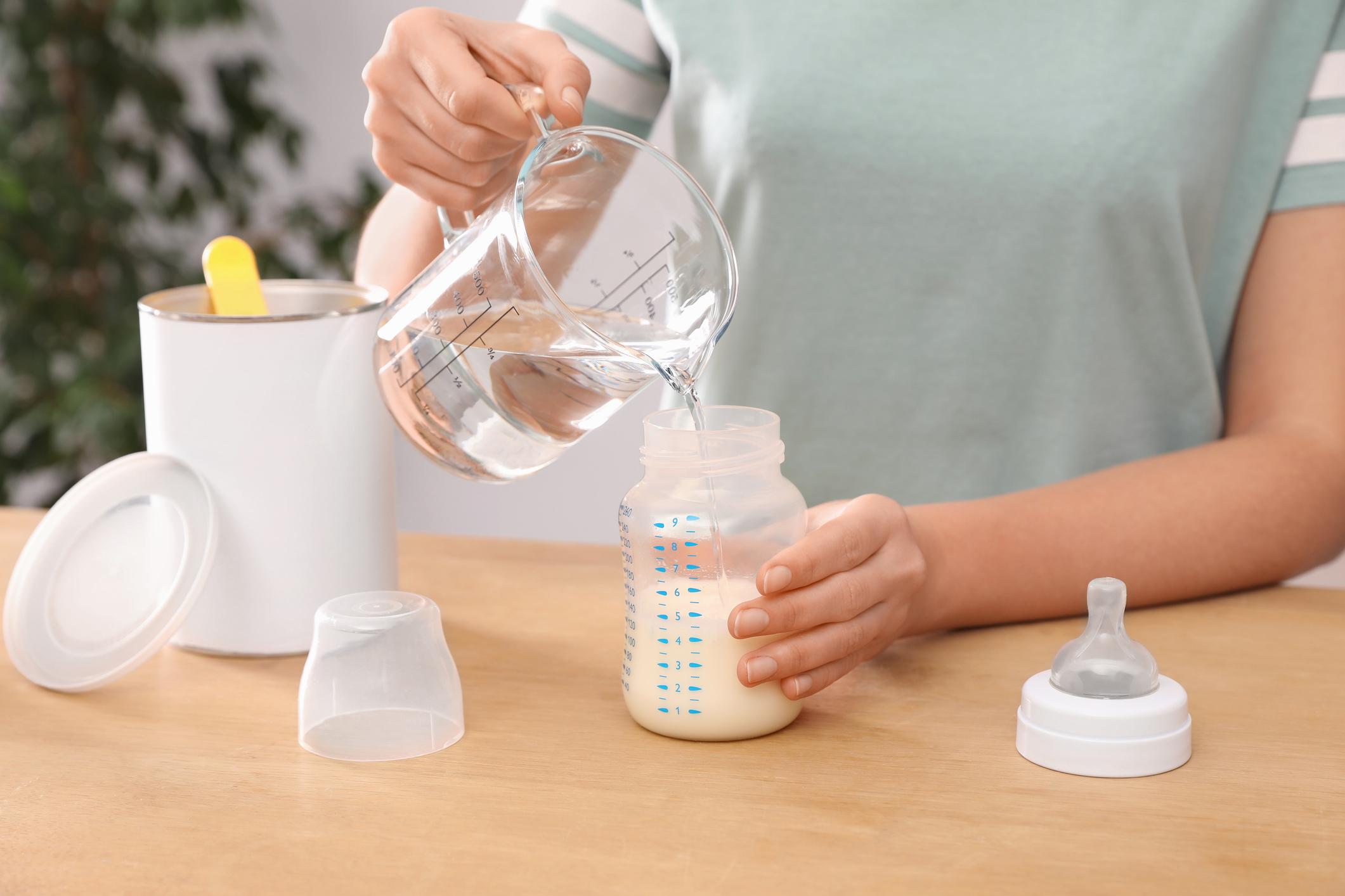 Woman preparing infant formula at table