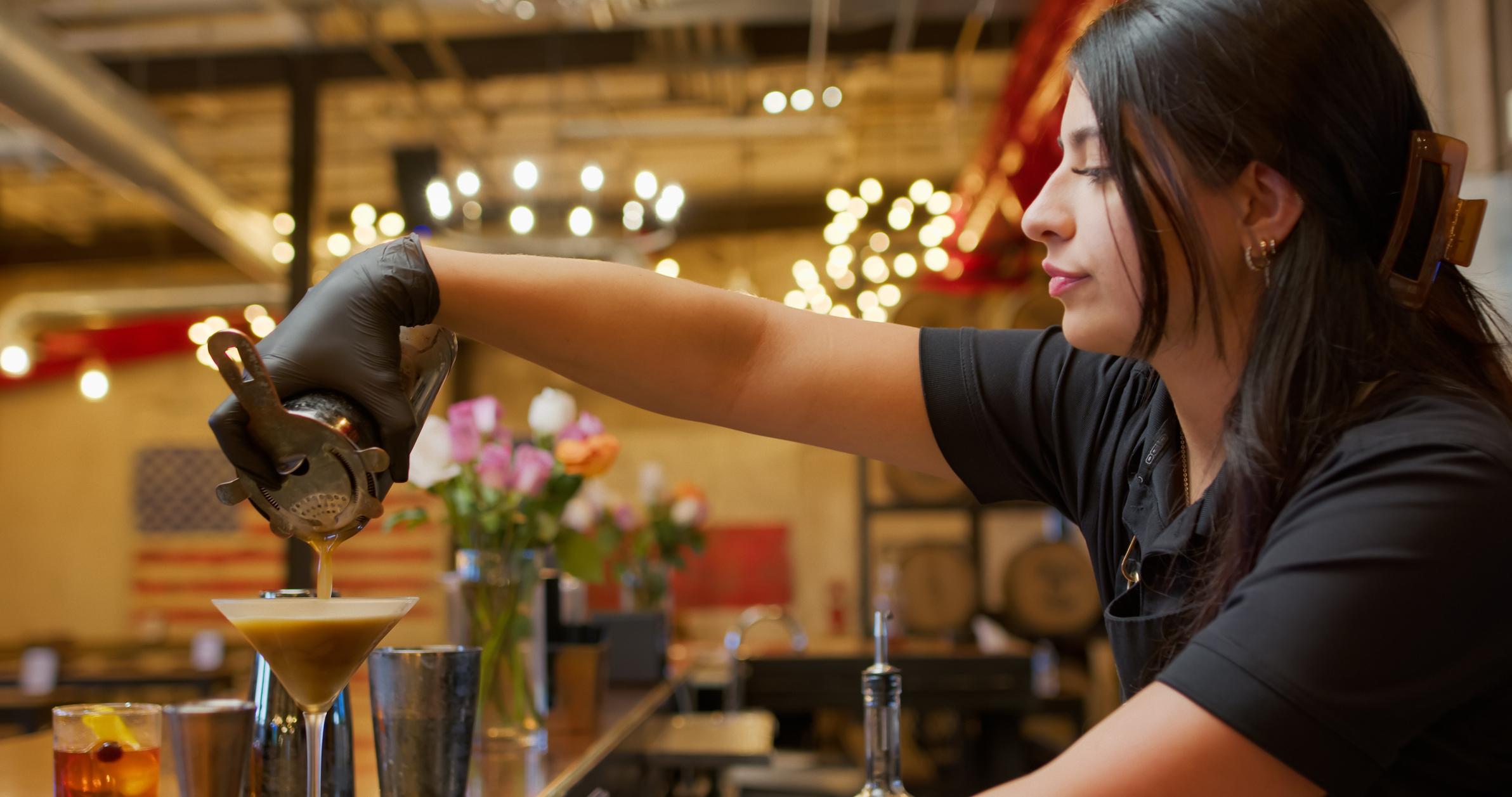 Female bartender pouring martini