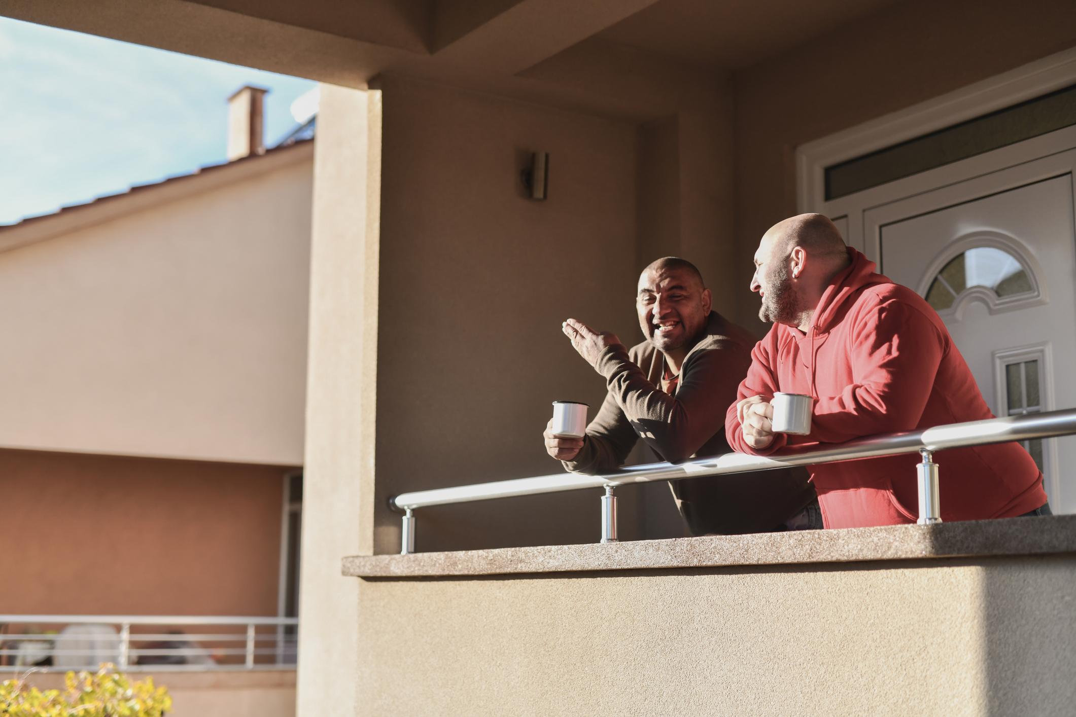 Two males enjoying coffee on their balcony