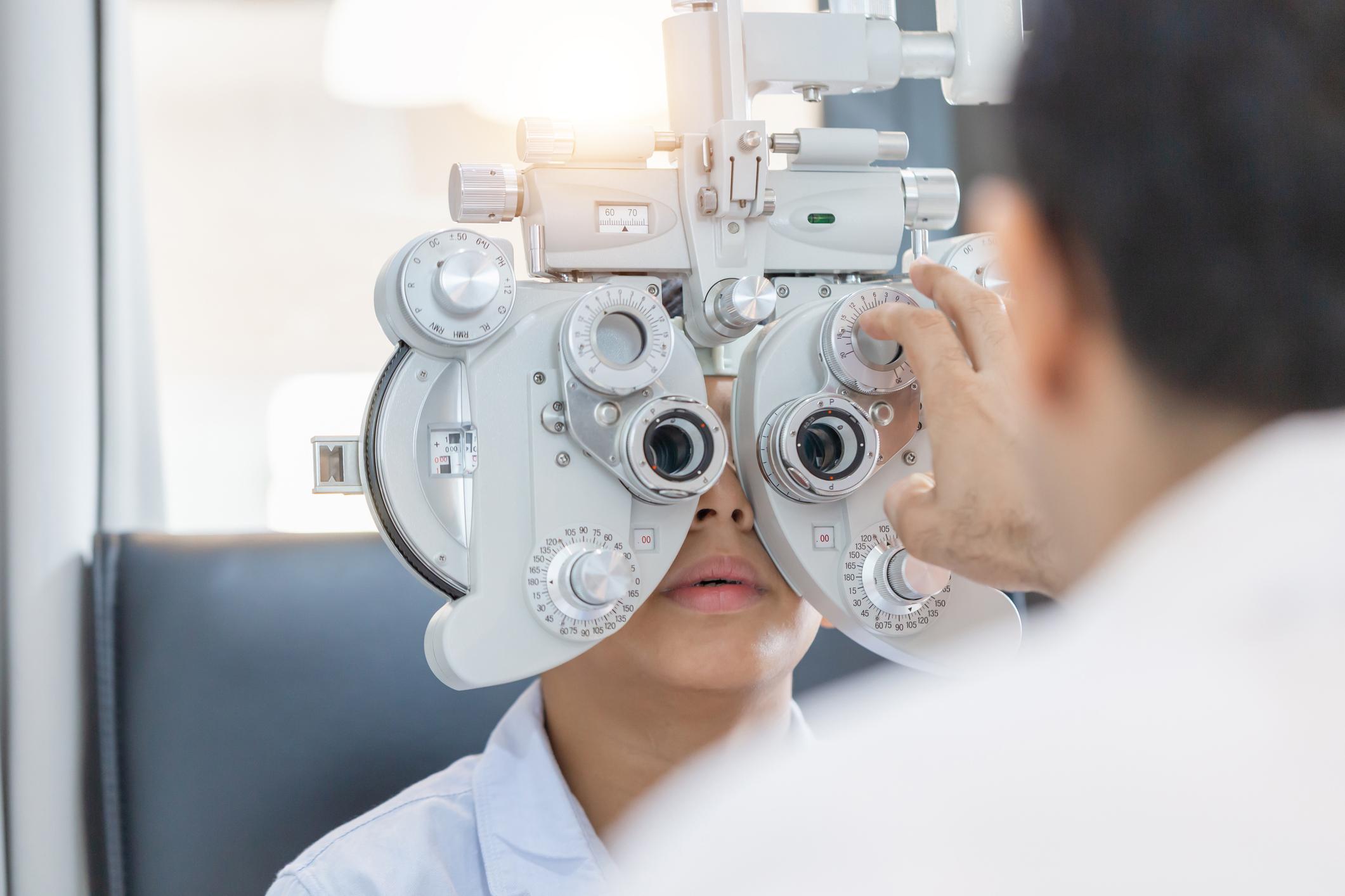 Boy doing eye test checking examination with optometrist