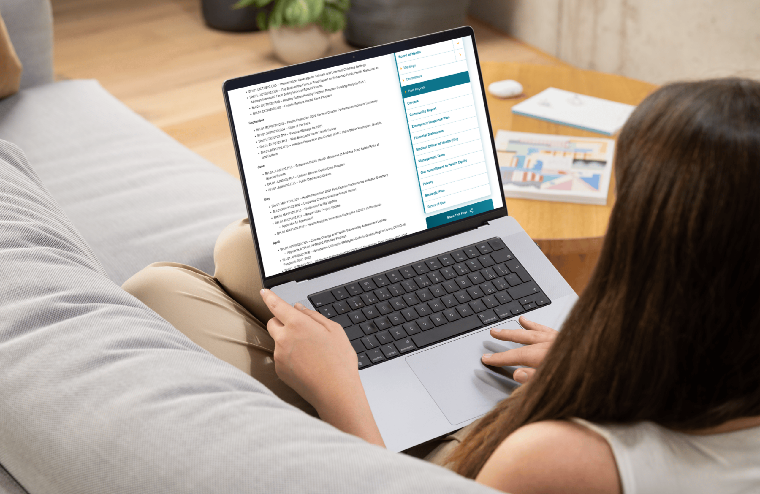 Woman sitting on couch looking at this web page on her laptop