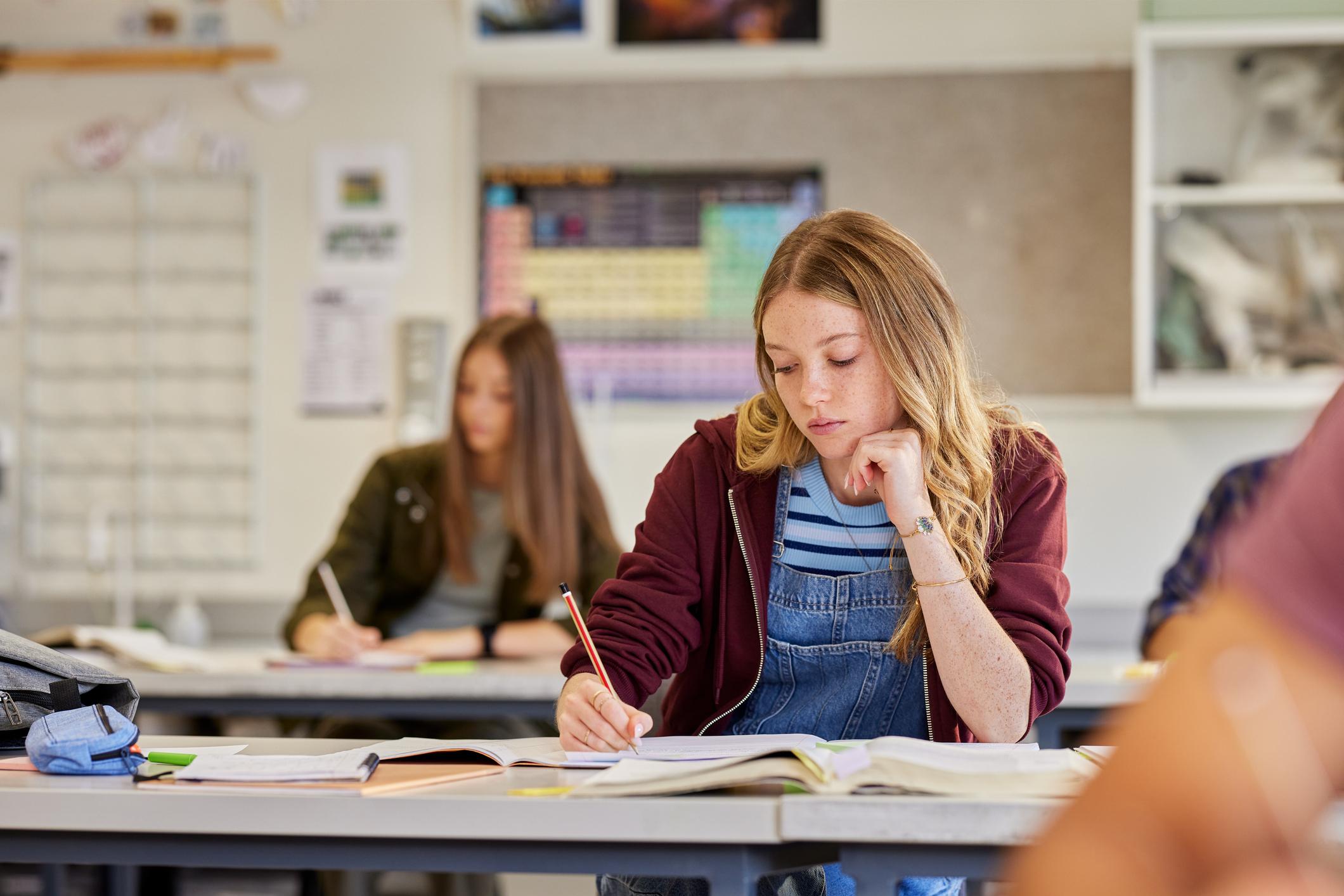 Young teen sitting in a classroom looking at her work