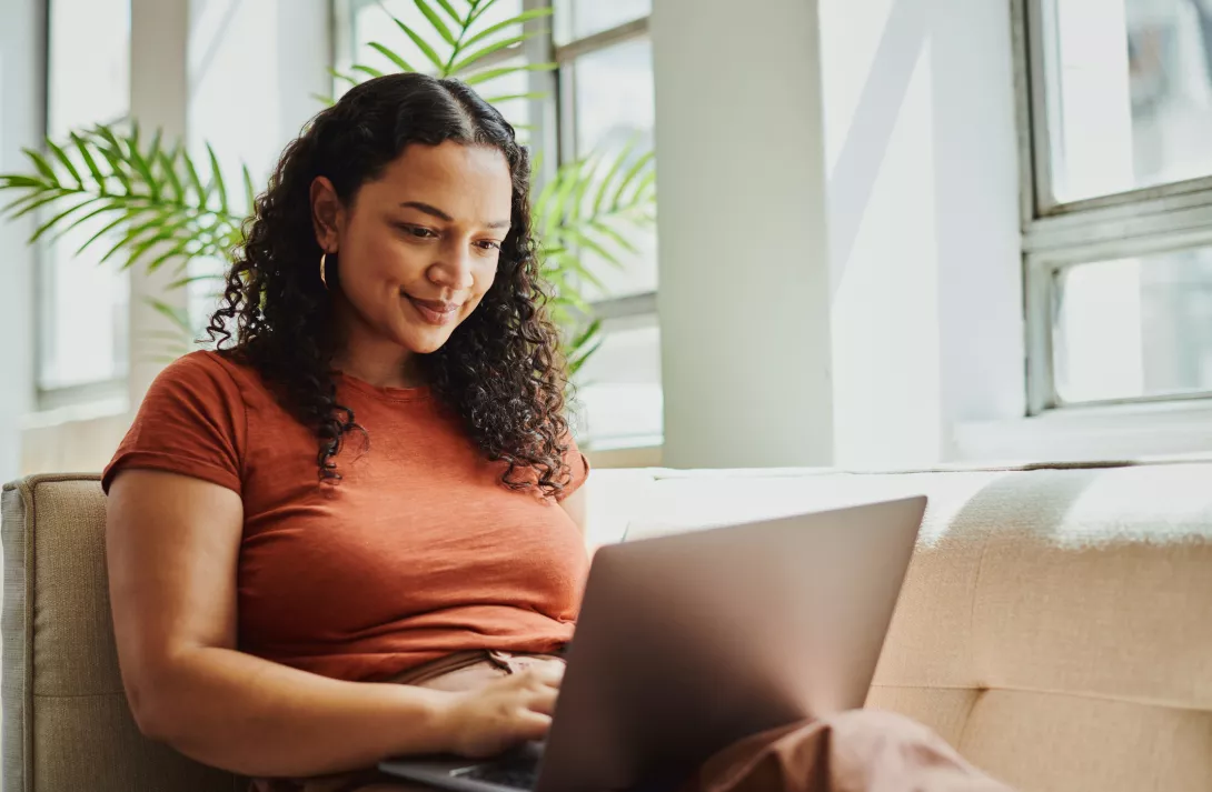 Young woman siting on couch on her laptop